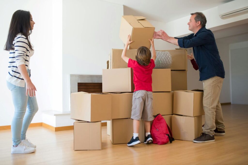man woman child arrange boxes in empty room